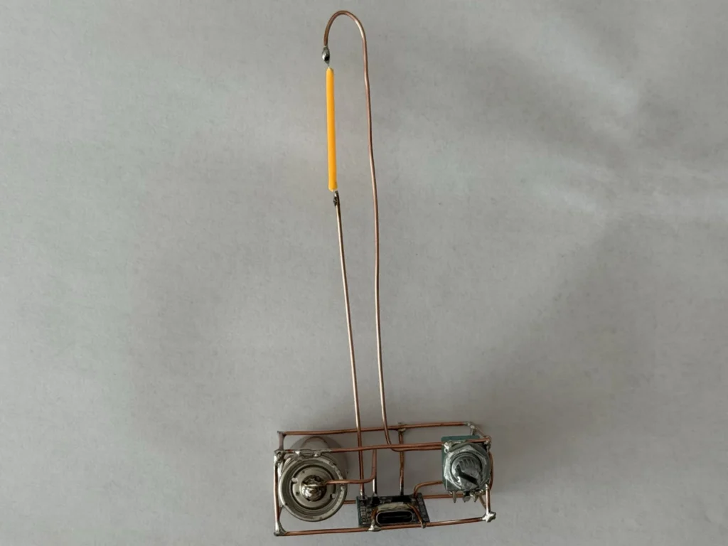 Front view of the copper wire lamp with the tall bent copper arm and the yellow LED filament soldered near the top