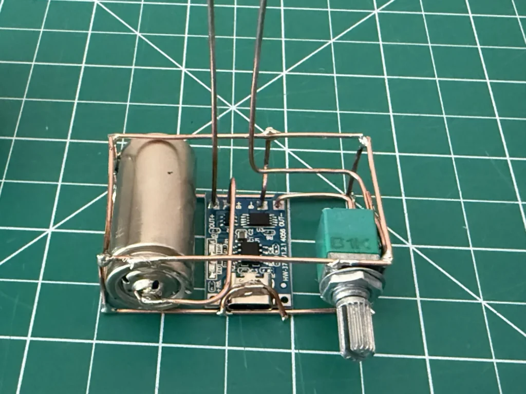 Close-up of the copper base: the 16340 cell, the HW-373 TP4056 charger board with its USB-C port, and the B1K potentiometer held by copper wires