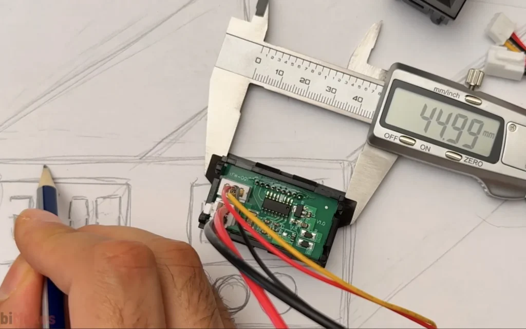 Digital calipers measuring the back of a digital meter module at 44.99 mm, with a pencil marking the sketch