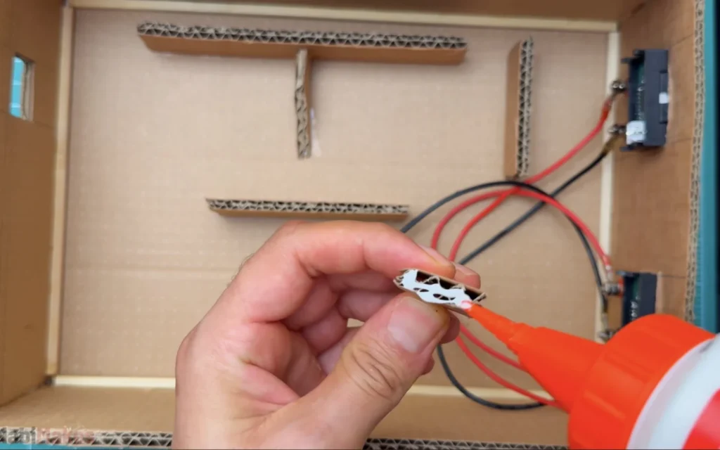 Applying wood glue to a strip of corrugated cardboard used as a mounting guide inside the case, with more guides already glued in