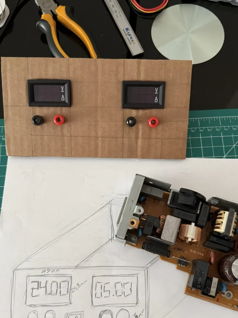 The finished cardboard front panel with meters and terminals above the pencil sketch and the printer power supply board