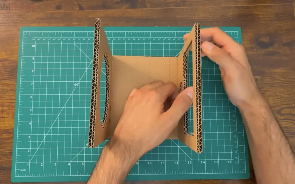 Partly glued cardboard box with the round front opening and the rectangular back opening standing on the bottom panel