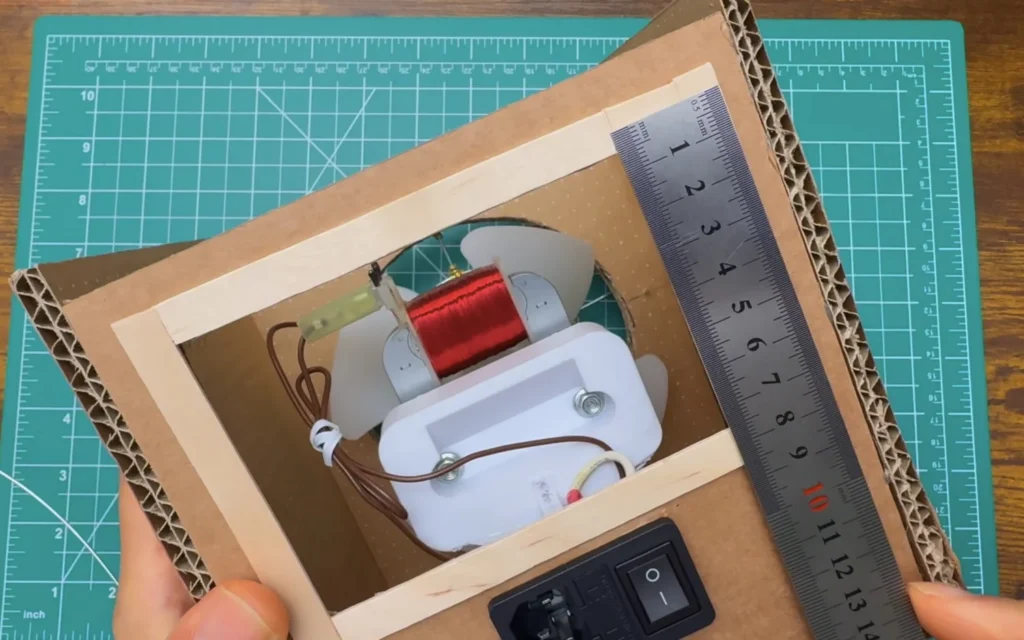 Steel ruler measuring the craft-stick framed opening on the back of the fan, with the motor visible inside