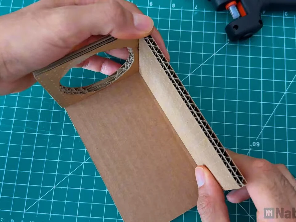 Front panel with round opening hot-glued at a right angle to a cardboard side panel