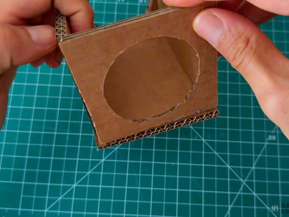 Back cardboard panel with a round opening being glued onto the box