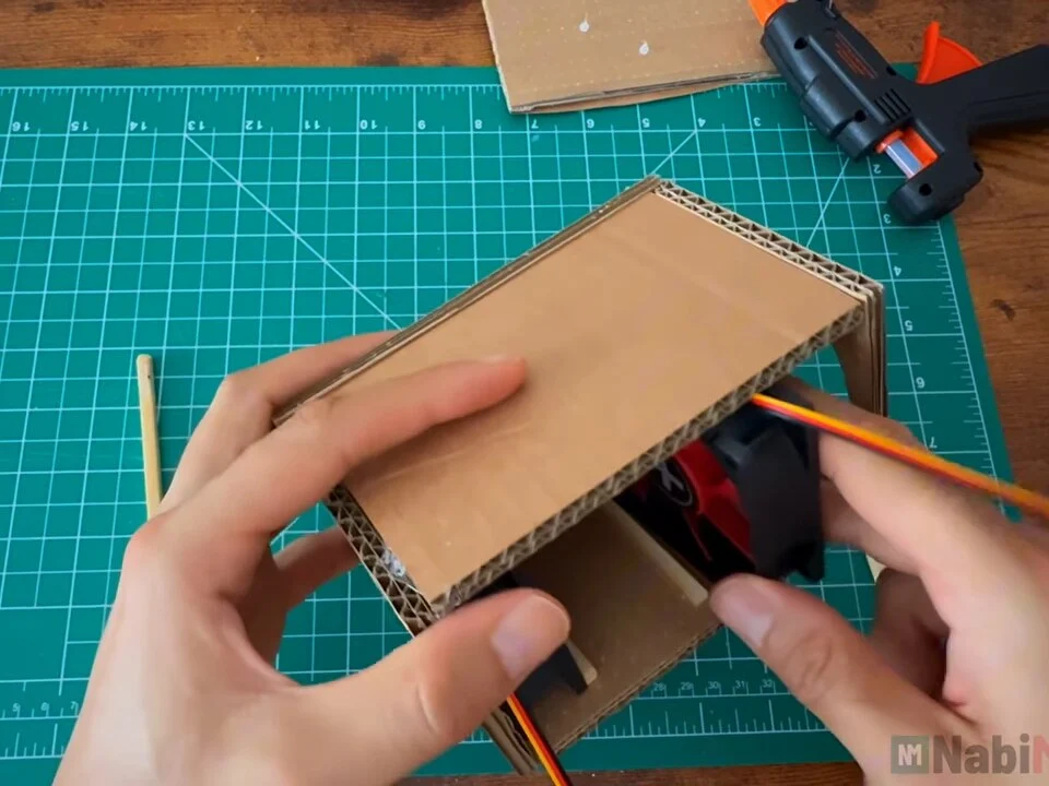 Checking that the top panel fits over the cardboard box with both fans inside
