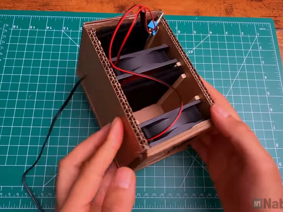 Box standing on its end with red wires from the fans connected to the toggle switch