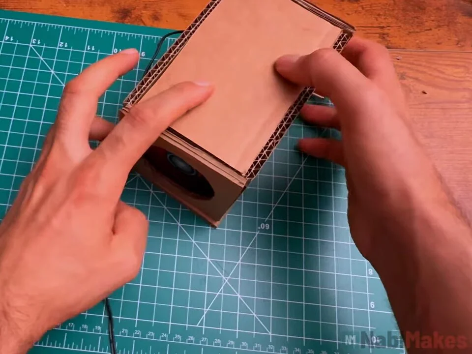 Pressing the top panel onto the cardboard box to close it