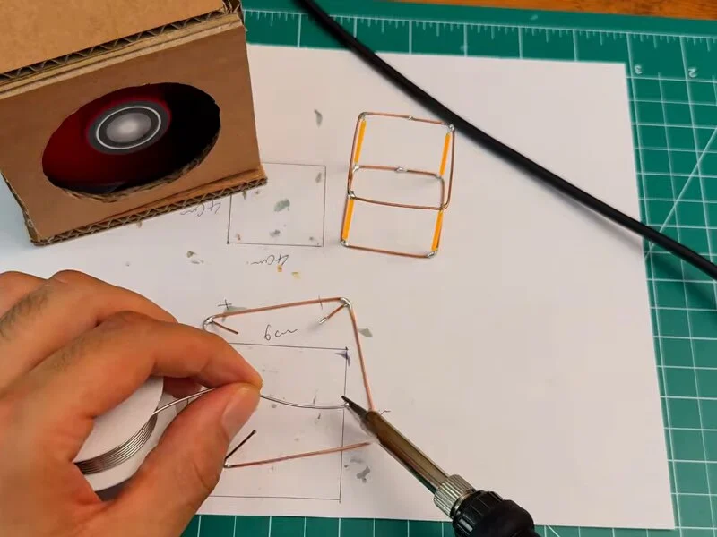 Soldering a copper wire frame on paper with the cardboard fume extractor running next to the work
