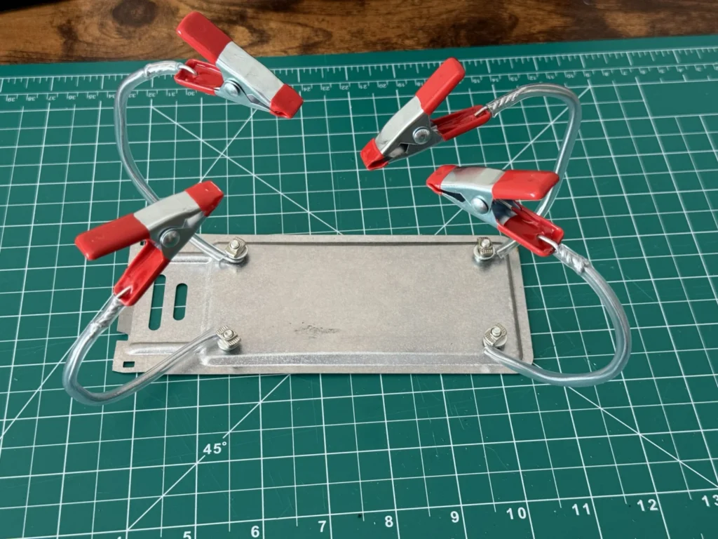Top view of the DIY helping hands showing four looped wire arms in clear tubing, each ending in a red spring clip