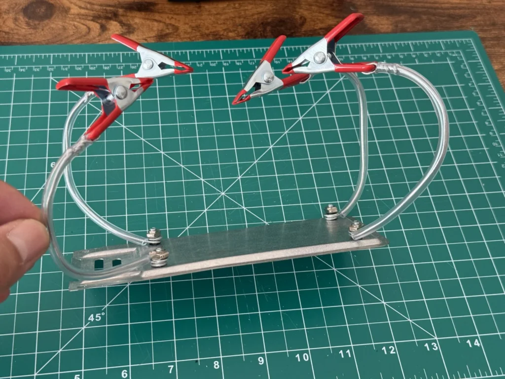 Side view of the DIY helping hands with the wire arms bolted to the corners of the metal plate using bolts, washers and nuts