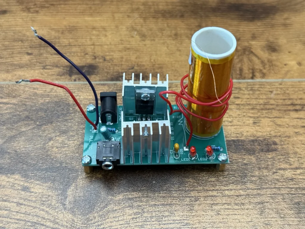 Side view of the Tesla coil board showing the red primary wire wound about three turns around the orange secondary coil