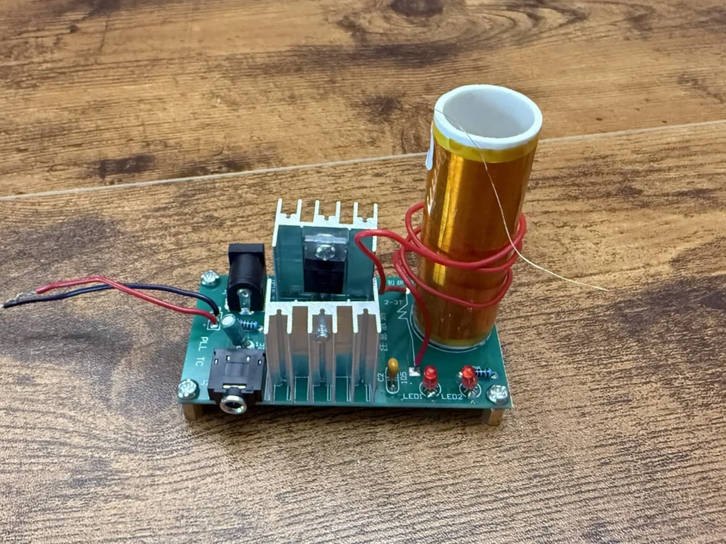 Finished mini Tesla coil board with the white-topped secondary coil, red primary winding and two aluminium heatsinks