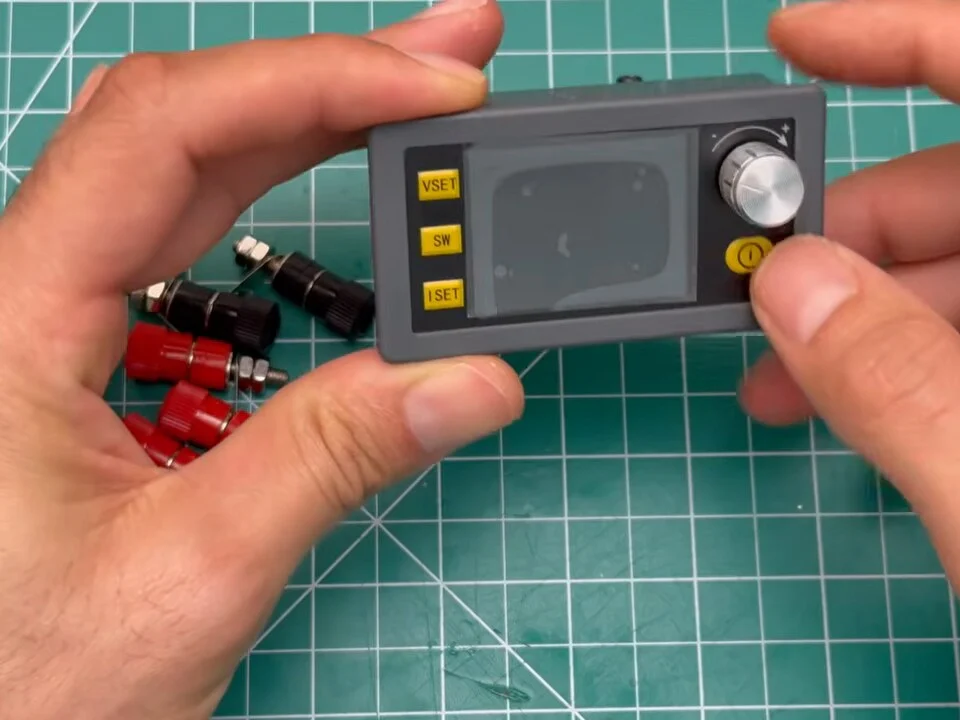SK120 buck-boost module with display, buttons and knob held in two hands