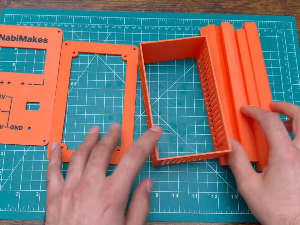 Orange 3D-printed front panel, back bezel and frame pieces on the cutting mat