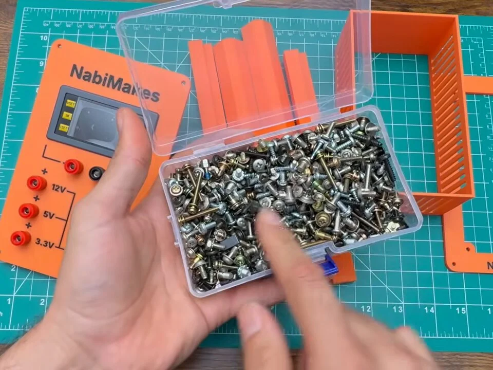 Box of salvaged screws next to the printed front panel and frame