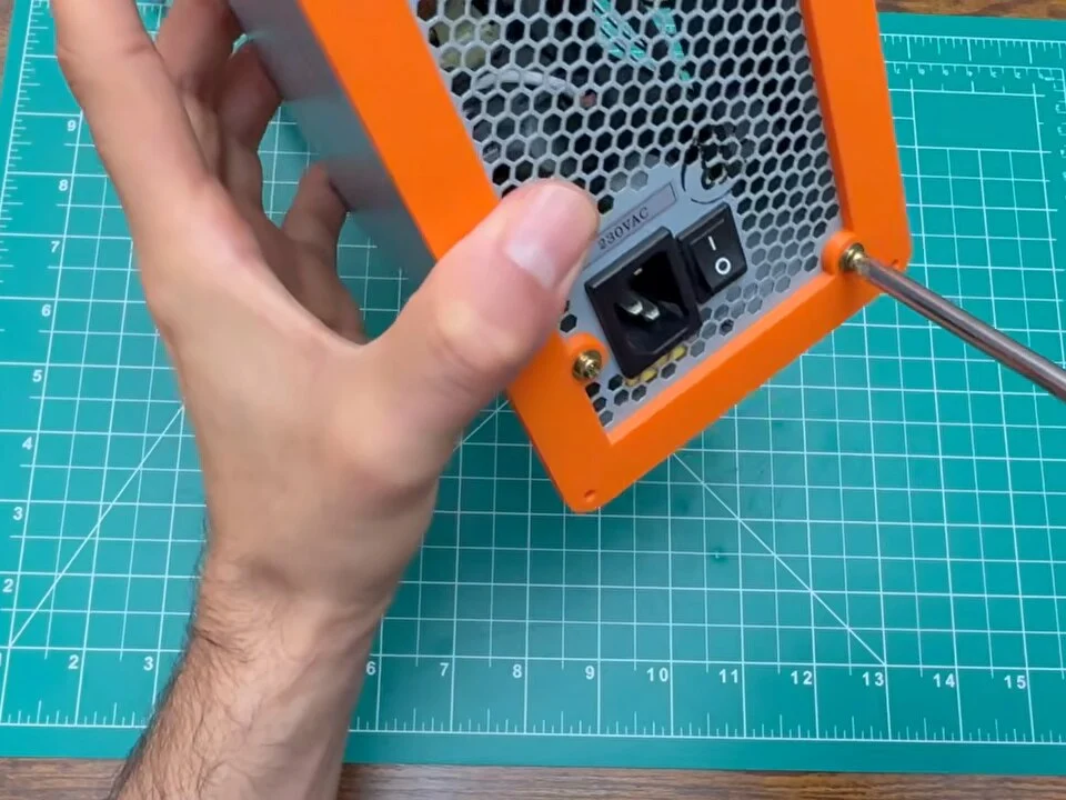 Printed back bezel being screwed around the power supply's mains inlet