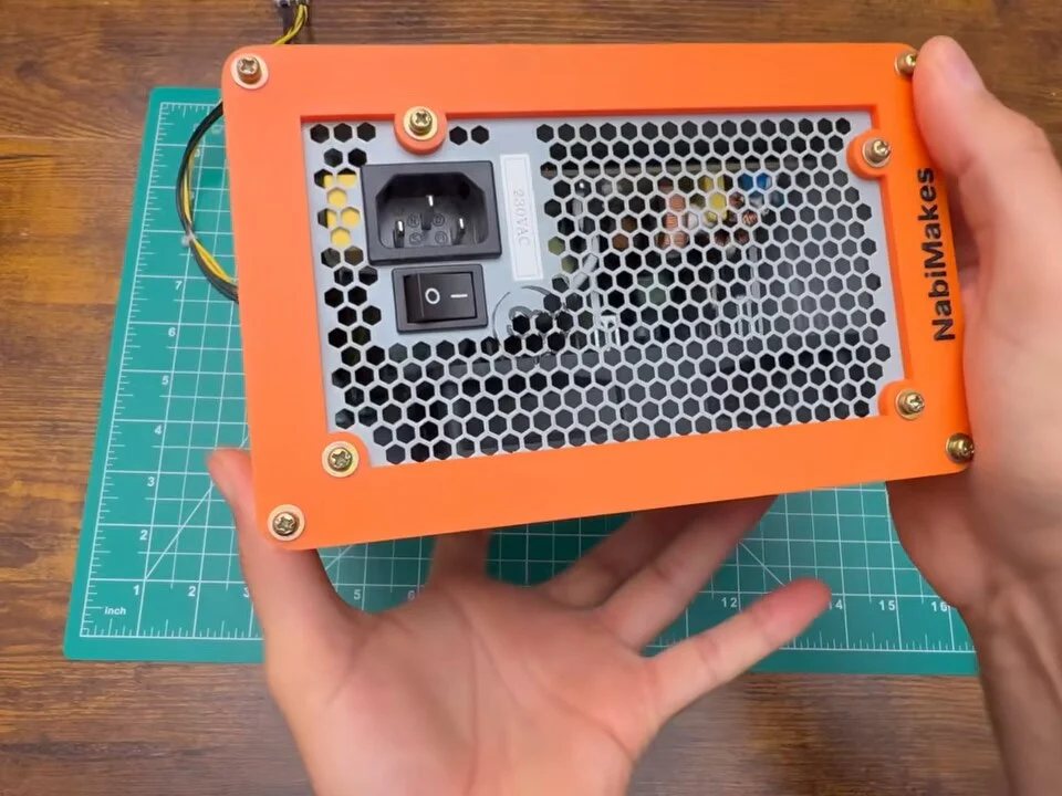 Back of the power supply framed by the orange printed bezel with the NabiMakes name