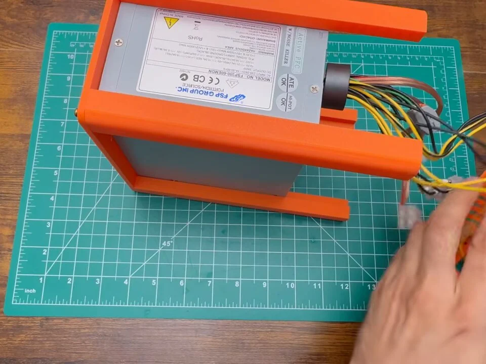 Orange printed frame fitted around the silver PC power supply case