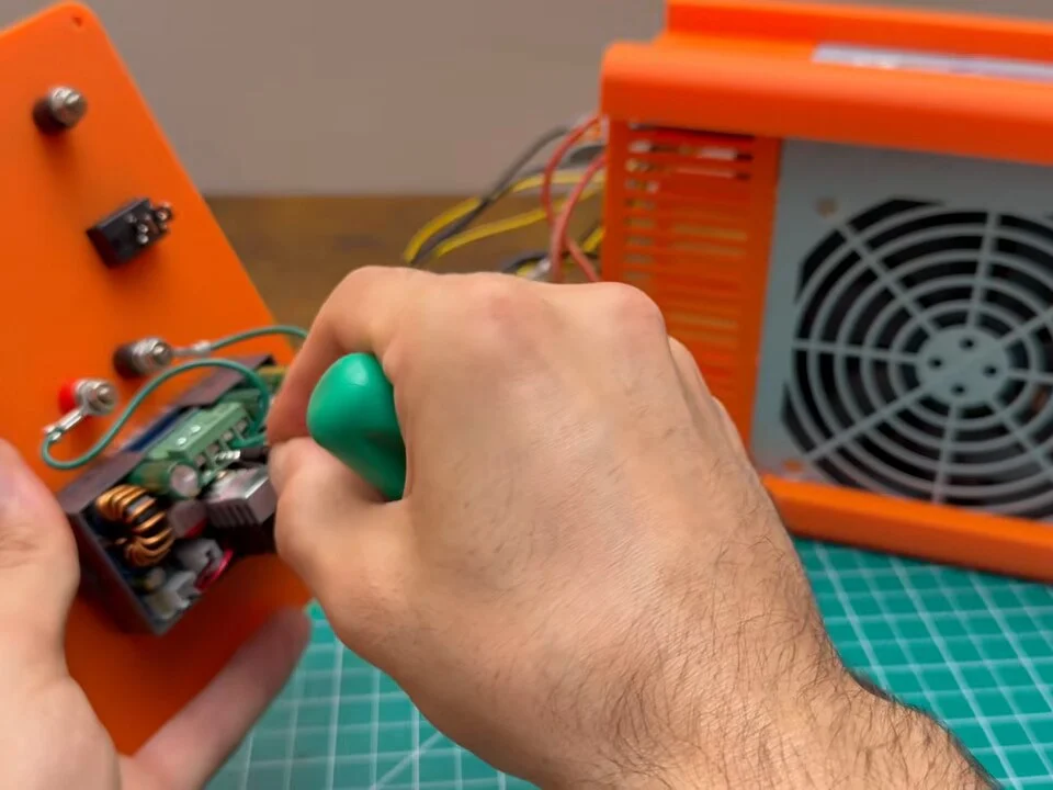 Screwdriver tightening the input terminals of the SK120 module on the back of the front panel