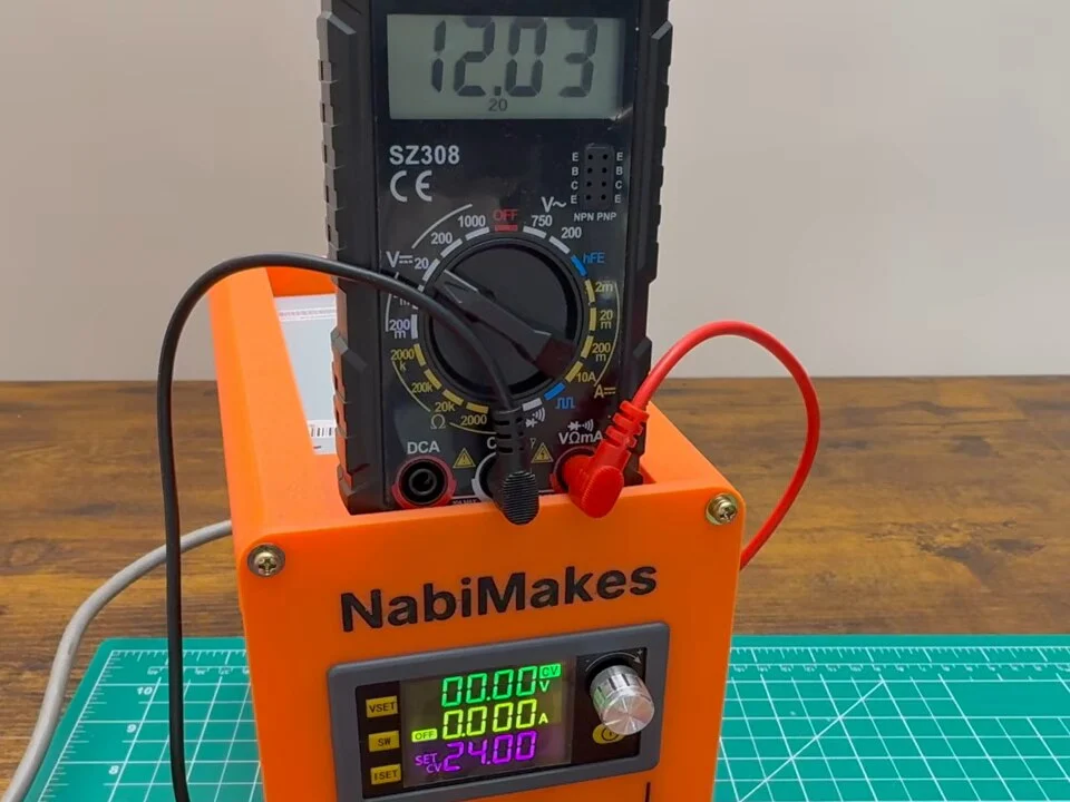 Multimeter on top of the bench power supply reading 12.03 V from the 12 V rail